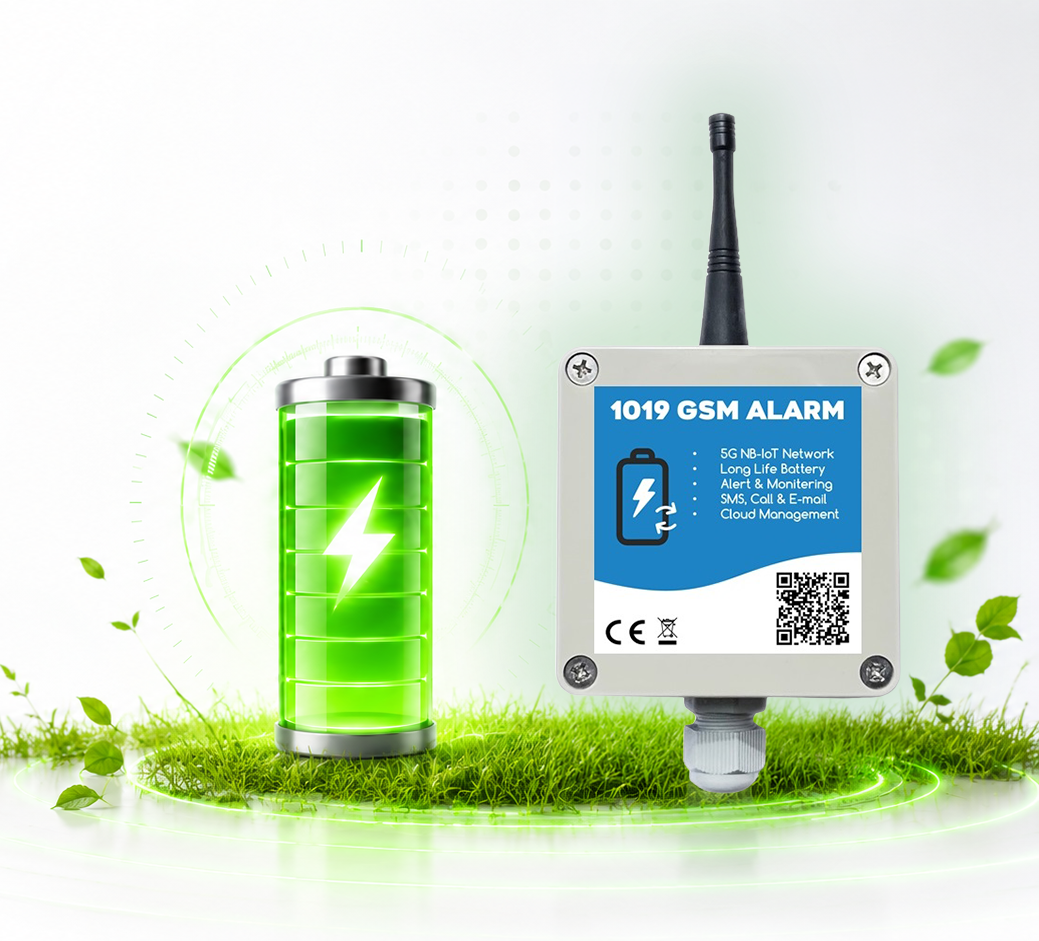 A green battery next to a grey GSM alarm box outdoors on the grass, glowing with a neon green light—likely a power supply for a monitoring system.